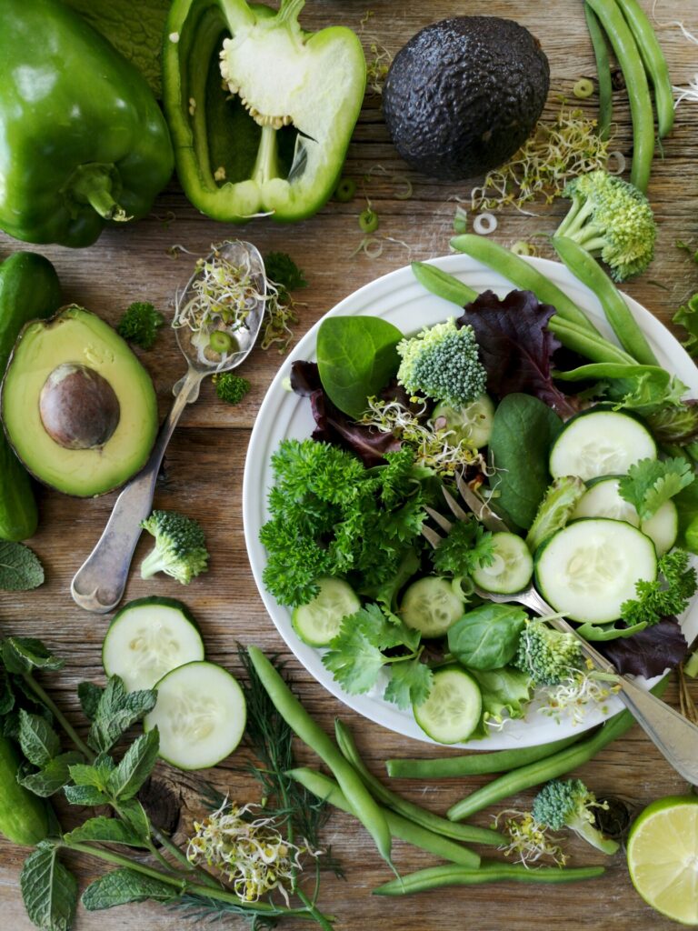 fiber rich vegetables including avocado and pepper on a wood table